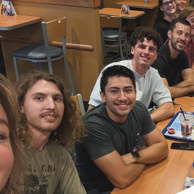 Young adults smiling around a table at The Well