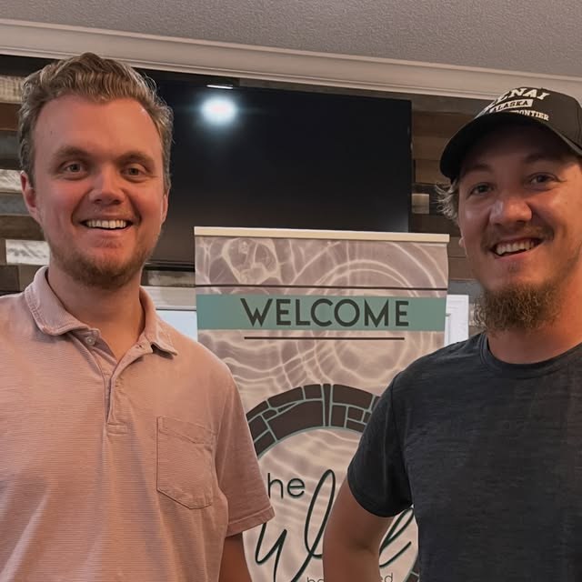 Two young men by The Well welcome sign