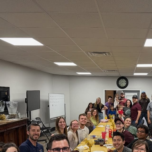 A large group of young adults at a long dinner table
