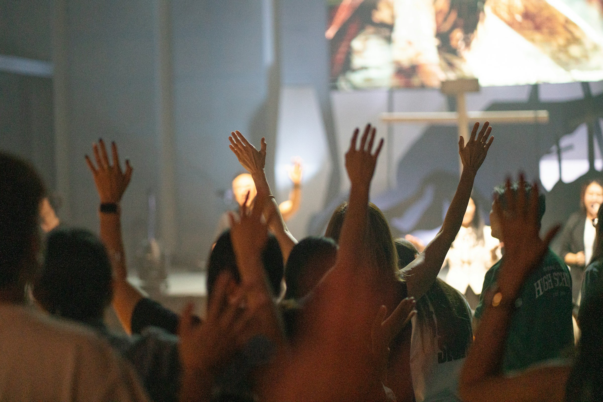 Congregation members raising their hands in worship during a church service