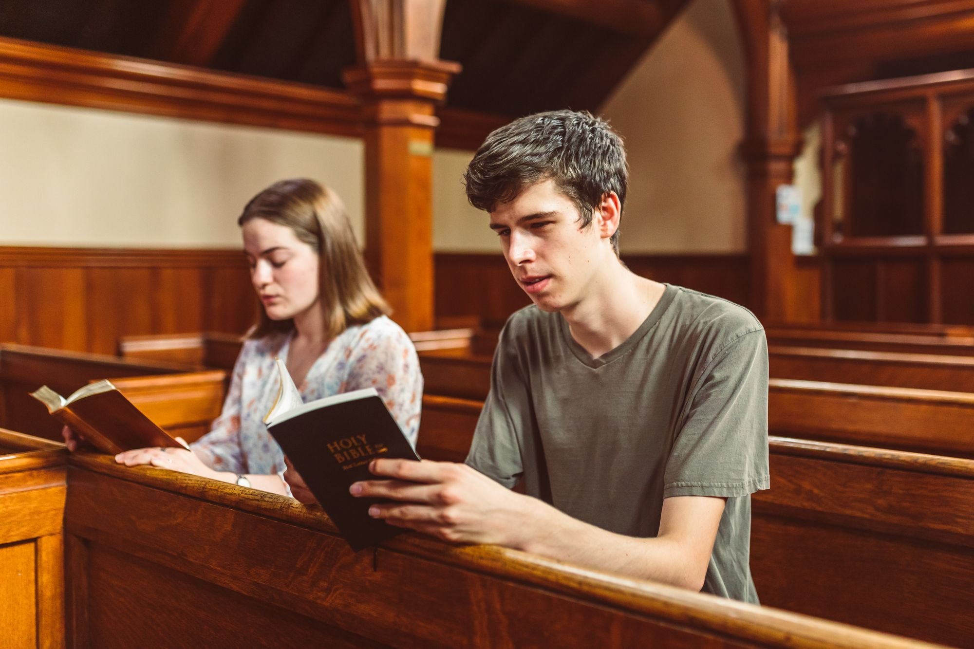 Two young adults reading Bibles in the pews