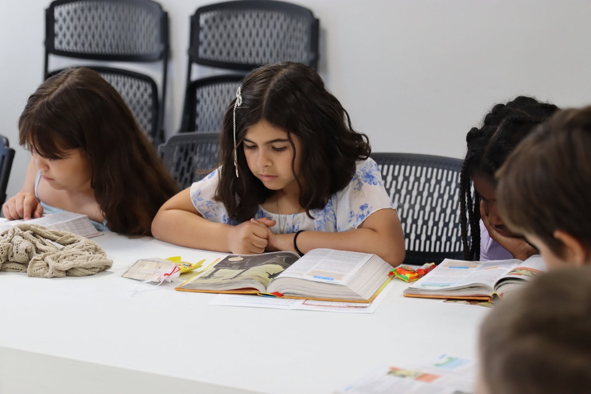 Children reading Bibles together at a classroom table